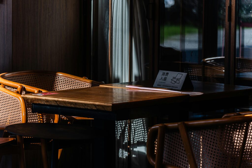 Sunlit cafe table setting with natural rattan chairs and empty seating, creating a cozy atmosphere.